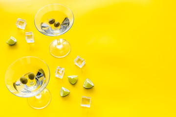 Martini with olives and ice on yellow background copy space