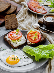 Breakfast with fried eggs, toast with cheese, lettuce, tomatoes and spices. A cup of espresso in the background. Close-up, shallow depth of field, breakfast concept.