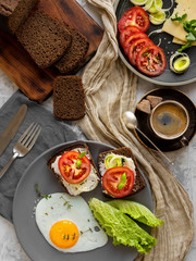 Breakfast with fried eggs, toast with cheese, lettuce, tomatoes and spices. A cup of espresso in the background. Top view, breakfast concept.