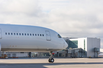 Nose and fuselage with airplane windows on the background of the airport terminal.