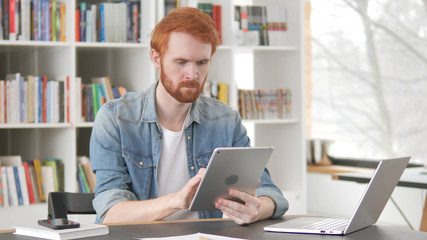 Young Casual Redhead Man Using Tablet