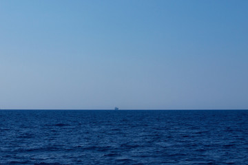 Ship sails in endless sea, shape in fog. Journey to blue.