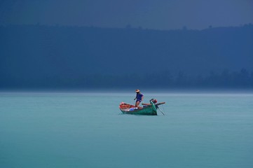 Fototapeta na wymiar Lonely fisherman on a boat after rain