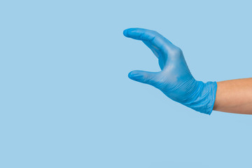Doctor's hand in a blue medical glove holds an object on a blue background. infection control. mocap, you can insert your product for advertising