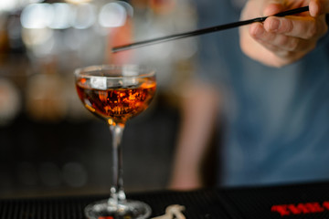 The barman is preparing a delicious alcoholic cocktail in a bar, restaurant.