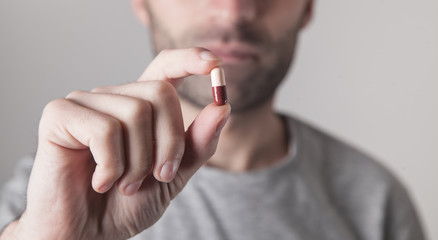 Close up of a man holding a pill.