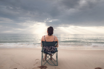 Fototapeta premium Freelancer Woman is Working on Tablet While Travel Vacation Trip at The Beach, Smart Woman is Using Tablet for Communication and Entertainment at Outdoor Sand Beach. Freelance and Relaxation Concept.
