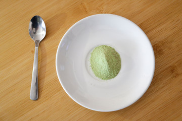 green tea matcha powder on white shiny dish