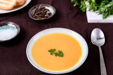 Healthy Vegetable Cream Soup in a bowl with toast grill on linen tablecloth. Vertical composition. Selective focus