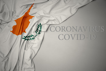 waving national flag of cyprus on a gray background with text coronavirus covid-19 . concept.