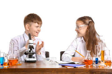 Cute little children studying chemistry at table against white background