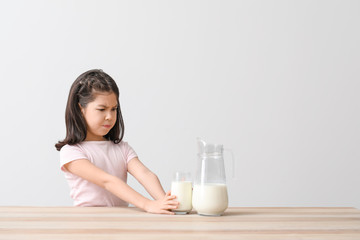 Cute Asian girl with dairy allergy on light background