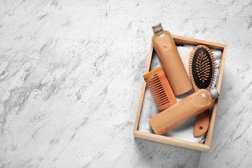 Box with shampoo, comb, towel and brush on light background