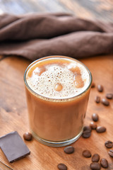Glass of tasty iced coffee on table