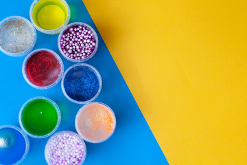 Flat lay with jars with slime. Multi-colored on a blue background. Top view copy space. Kids crafts...