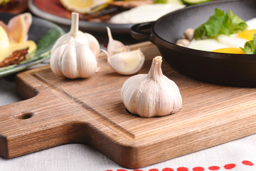 Fresh garlic and spices on wooden board with other dishes on table. Side view. Ukrainian cuisine.