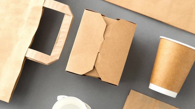 package, recycling and eating concept - disposable paper container for takeaway food, coffee cups and bags on grey background