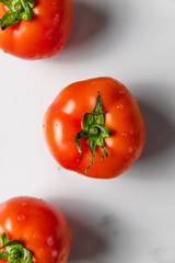 Fresh ripe tomatoes on light marble background. Summer organic vegetable for salad