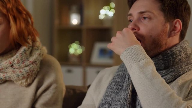 health, flu and people concept - sick young couple at home in evening