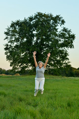 Mature woman jumping on fresh air in summer