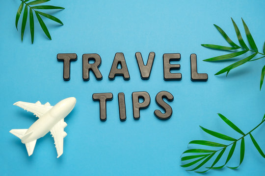 summer flat lay travel tips note , plane and palm leaves on a blue background