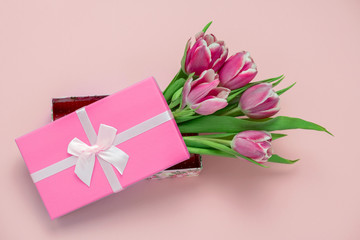 top view pink tulips in a box with pink satin ribbon bow on a pastel pink background