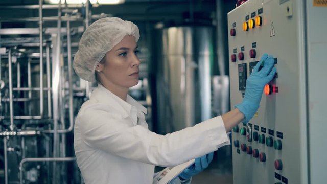 Female worker is operating a control panel in a factory unit