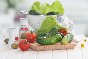 Summer vegetables on white table with tomatoes, salads, olives and cucumbers