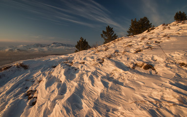 Winter sunset snow mountain view on the background of hills under colorful sky