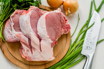 Raw pork chops, parsley, chives and onions. On a cutting board. Ready for cooking  