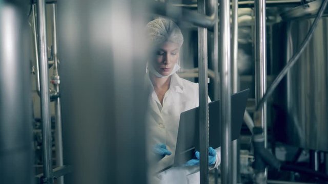 Lady expert with a laptop is inspecting plant machines