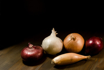 Five different onions on wooden table