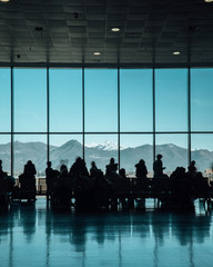 Silhouette of a group of people waiting in an airport Bergamo with a beautiful mountain view....