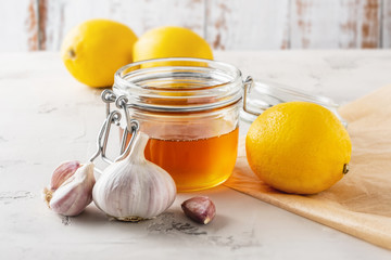 Alternative medicine, natural home remedy for cold and flu. Glass jar with honey, lemon and garlic - obrazy, fototapety, plakaty