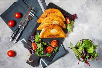 Latin American, mexican, chilean food. Traditional baked pastry empanadas with beef meat on concrete background