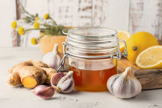 Alternative medicine, natural home remedy for cold and flu. Glass jar with honey, ginger, lemon, garlic and camomile
