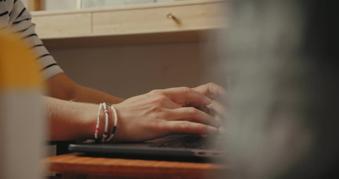 Cinematic warm temperature shot of female hands work on laptop keyboard during self isolation work from home quarantine. Freelancer or office worker during video conference with colleagues