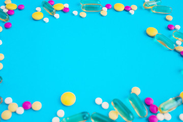 Spilled colored medications and pills on a blue background. Pharmacology and medicine struggle for health.