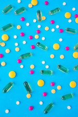Spilled colored medications and pills on a blue background. Pharmacology and medicine struggle for health.