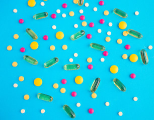 Spilled colored medications and pills on a blue background. Pharmacology and medicine struggle for health.