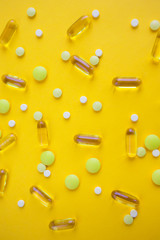 Tablets, pills and capsules on yellow background. Copy space.