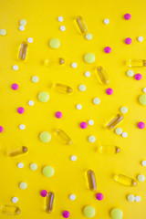 Tablets, pills and capsules on yellow background. Copy space.