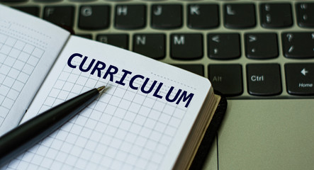 notebook with the word CURRICULUM , on the background of a laptop