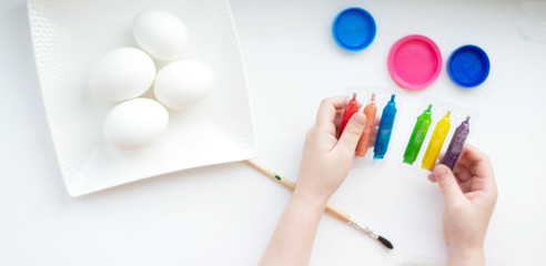 Hands of a little girl draws Easter eggs on a white background.