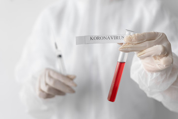 in the laboratory, the doctor holds a test tube in his hands. The inscription coronavirus.