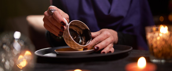 Woman fortune teller divines on coffee grounds at table with ball of predictions