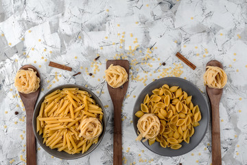 fettuccine paste on grey ceramic dishes and wooden spatulas and various other pastes on a...