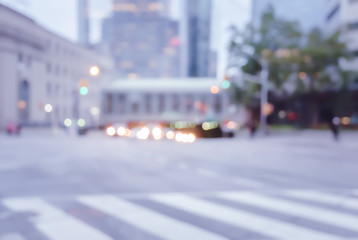 Blurred pedestrian crossing street in the city with traffics light colorful bokeh and buildings background.