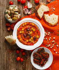 Hummus with dried tomatoes on a white plate, top view. Delicious appetizer, party food