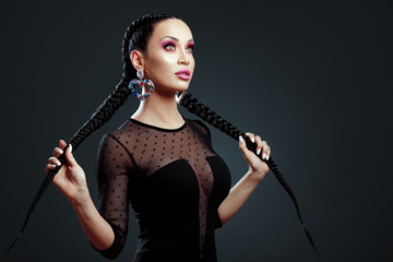 Beauty portrait of woman with braids and beautiful makeup in studio on dark background - obrazy, fototapety, plakaty